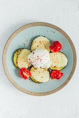 Poached egg with fried zucchini, mozzarella cheese, tomatos and red chili flakes. Top view.