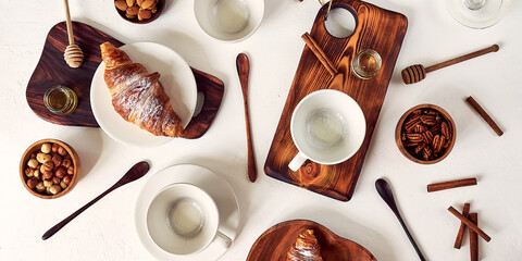 pattern, composition of coffee cups and croissants, nuts, honey and wooden spoons, top view on a white background