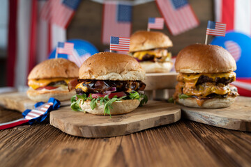 Fourth of July celebration. American flag and decorations. Burgers on rustic wooden table.