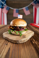 Fourth of July celebration. American flag and decorations. Burgers on rustic wooden table.