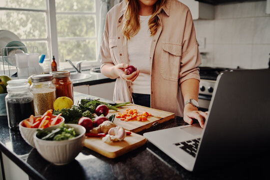 Young female blogger searching online browsing for recipes to prepare salad of fresh vegetables and post on social media in vlog - new hobby during isolation