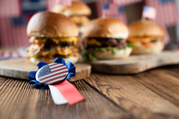 Fourth of July celebration. American flag and decorations. Burgers on rustic wooden table.