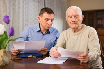 Adult man with elderly father analyzing papers