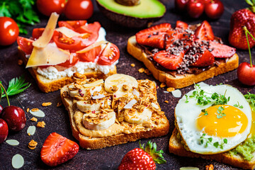Breakfast different toasts with berries, cheese, egg and fruit, dark background. Breakfast table concept.