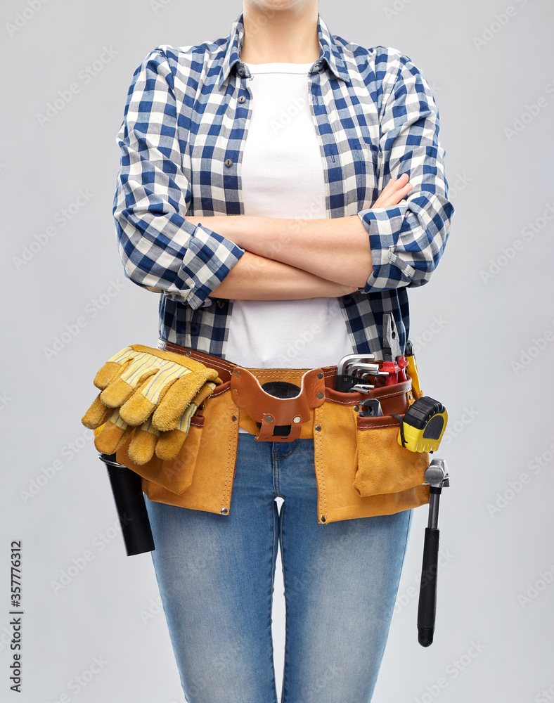 Wall mural repair, construction and building concept - woman or builder with working tools on belt over grey background