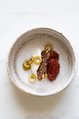 olives, dried tomatoes, cream cheese and snack on white marble background with copy space