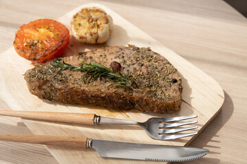 Beefsteak with herb garlic and tomato on wooden cutting board with daylight concept