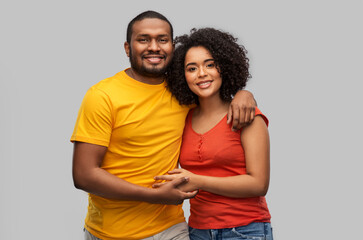 relationships and people concept - happy african american couple hugging over grey background