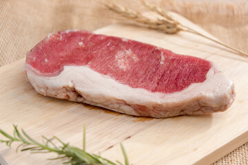 Raw beefsteak on wooden cutting board. Close up. Wooden Background