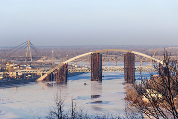 Tied arch bridge across winter river during construction, Kyiv, Ukraine