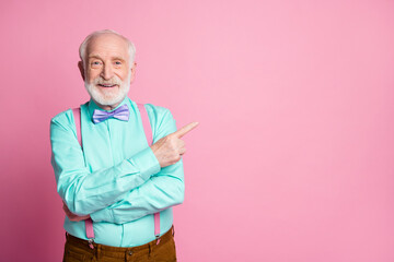 Photo of cool stylish look grandpa indicating finger empty space offer black friday low prices wear mint shirt suspenders violet bow tie isolated pastel pink color background - obrazy, fototapety, plakaty