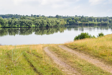 Hill with field road over reservoir with trees overgrown shores