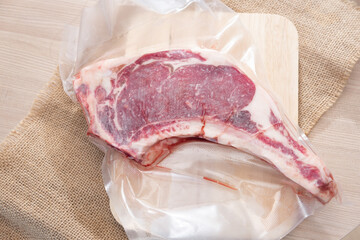 Raw Tomahawk steak in the pack on a wooden background
