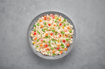 Veg Fried Rice in gray bowl on concrete table top. Veg Fried rice is indo chinese cuisine dish. Indian vegetarian meal. Asian food. Top view