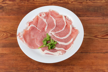 Tenderized boneless raw pork chops on dish on rustic table