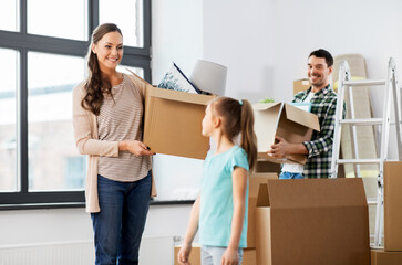 Fototapeta na wymiar mortgage, family and real estate concept - happy mother, father and little daughter with stuff in boxes moving to new home