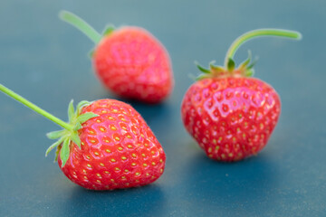 Drei reife Erdbeeren auf taubenblauem Untergrund