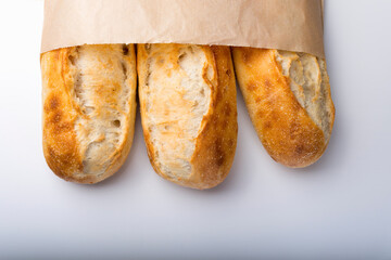 French bread rolls in the paper bag isolated on light background.
