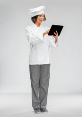 cooking, culinary and people concept - happy smiling female chef in toque with tablet pc computer over grey background