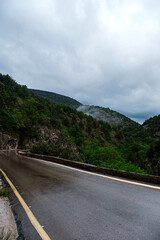 Fototapeta premium Asphalt road through the mountains forest in rainy season