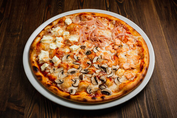 Ham, fish, mushroom and feta cheese pizza, wooden background, low key
