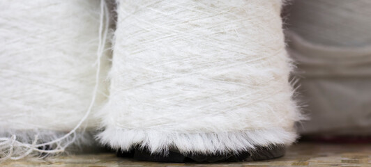 fluffy white yarn on bobbins close up as background