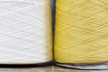 white and yellow yarn on bobbins close up