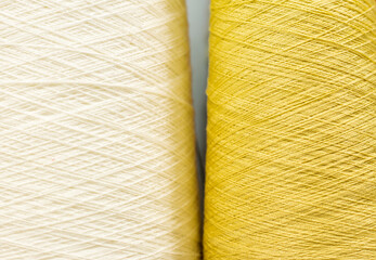 white and yellow yarn on bobbins close up as background