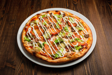 Bacon, meat, pickles, tomato, lettuce pizza with mayonnaise, wooden background, low key