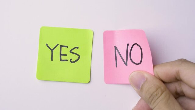 Close up tearing off a pink sticky note with the word No. Concept of choice.