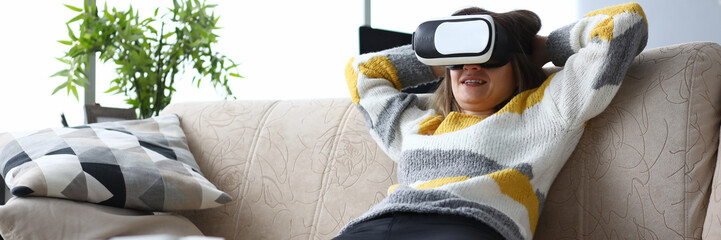 Girl sits sofa home relaxes with virtual glasses. World transmitted to man through his sensations...