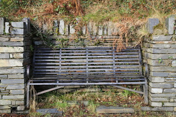 A metal bench beside a country road on the outskirts of a Welsh village.