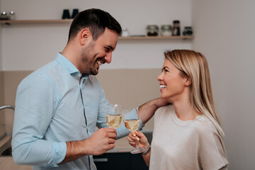 Cheerful couple drinking white wine and toasting.