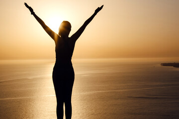 Fototapeta premium strong confidence woman open arms under the sunrise at seaside