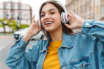 Image of woman smiling while listening music with wireless headphones