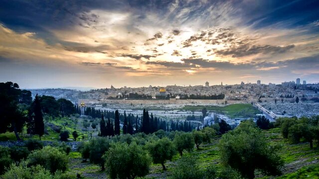 Dramatic sunset time lapse of Jerusalem's Old City, view from the Mount of Olives over the Dome of the Rock and the Temple Mount, with an olive grove in the foreground; Jerusalem Israel