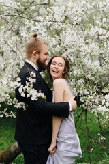 young beautiful couple in the garden against the background of cherry blossoms