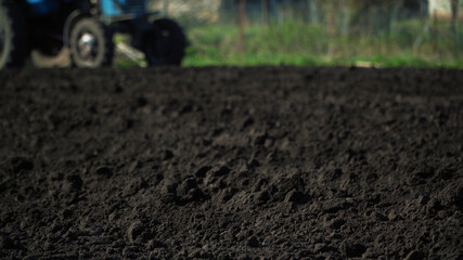 The tractor cultivates and cuts furrows in the field. Tractor work in the black soil field in the...