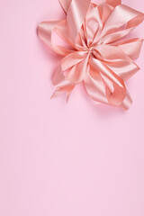 Satin pink bow on pink background with space for text.