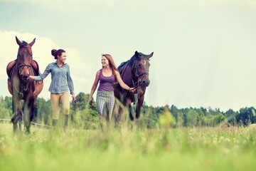 Young girls riding horses bareback in field