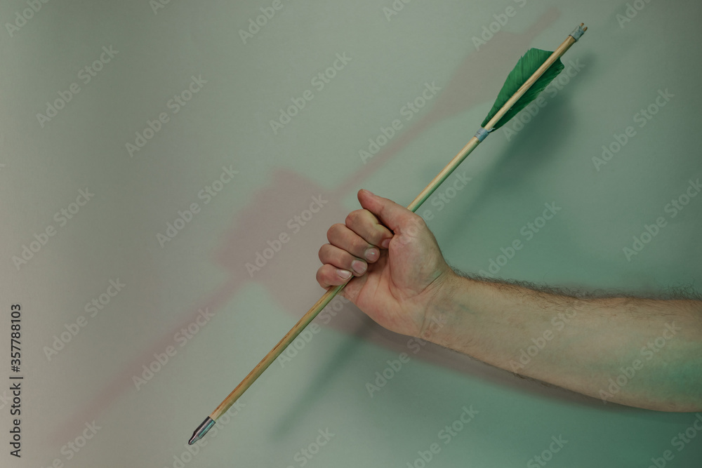 Poster Hand holding old green arrows in the color light. Beautiful old arrow minimal in neon light. Minimalism retro style concept. Background pattern for design.