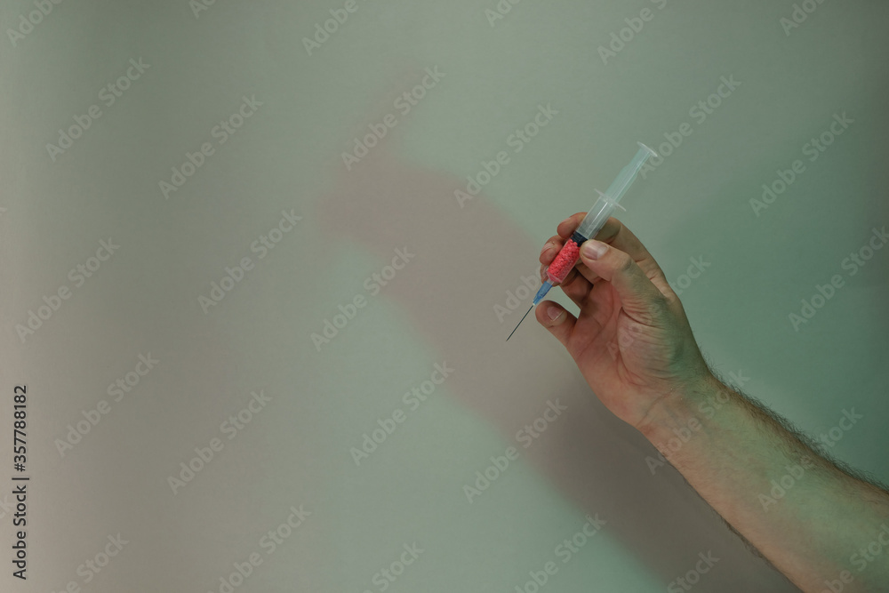 Poster hand holding creative syringe with red vaccine in the color light. beautiful. minimal in neon light.
