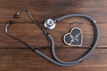 Workplace of a doctor. Stethoscope and little heart on wooden desk background