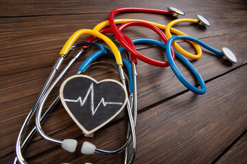 Workplace of a doctor. Colorful Stethoscopes and little heart on wooden desk background -...