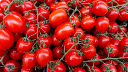 Cherry tomatoes on a branch. Tomato background. Ripe juicy tomatoes for salads and restaurants on the counter in the market. Top view photograph of cherry tomatoes with copy space