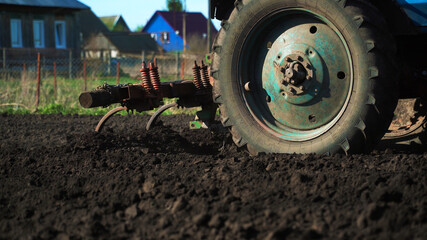 The tractor cultivates and cuts furrows in the field. Tractor work in the black soil field in the...