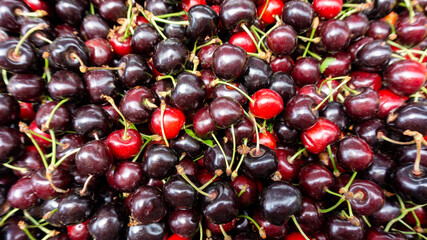 Cherry background for printed materials, wallpaper with copy space. Top view of juicy ripe sweet cherries.  Ripe cherries abundance in the summer market.