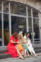 Women shopping. Three elegant woman sitting in a city. Ladies in a stylish dress. Women with a little dog