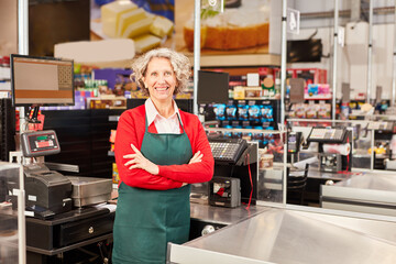 Verkäuferin mit verschränkten Armen an der Kasse