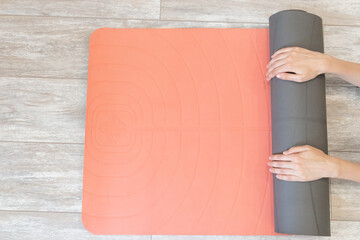 Woman rolling up yoga mat - top view